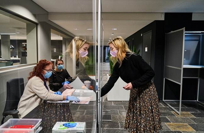 A poling station official checks the ID of a Dutch voter