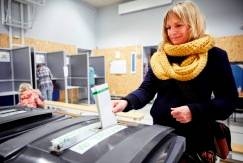 photo of woman putting her ballot in ballot box